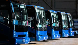 Row of blue charter buses staged in a depot, ready for dispatch