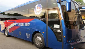 Lorenz Bus Service motorcoach with blue and red livery parked at a transportation staging area
