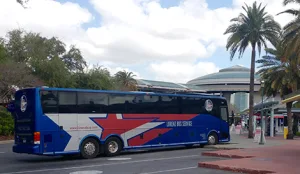 Lorenz Bus Service motorcoach parked at a Florida venue drop-off area with palm trees and a domed building in the background