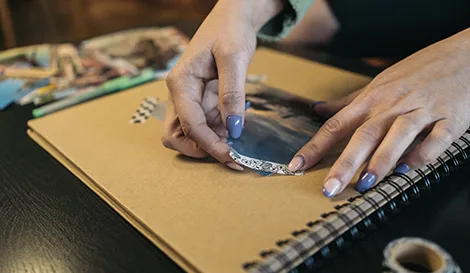 Person placing a decorative photo corner on a picture in a scrapbook album