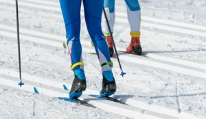 Cross-country skiers in racing suits gliding along groomed snow tracks during a competitive event