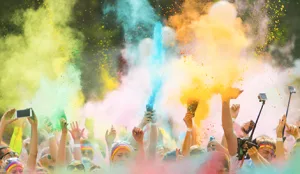 Crowd of people throwing colorful powder into the air at a festive outdoor event