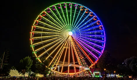 and were not provided, so I'll treat this as an informative image. Colorful illuminated Ferris wheel glowing against a night sky at an outdoor fair or amusement park