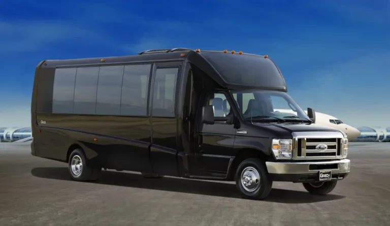 Black Grech Motors mini coach bus on a tarmac with an airplane visible in the background