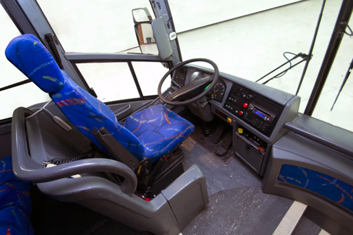 Coach bus driver's area showing the seat, steering wheel, and instrument panel