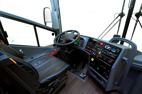 Charter motorcoach driver cockpit with steering wheel, dashboard controls and operator seat