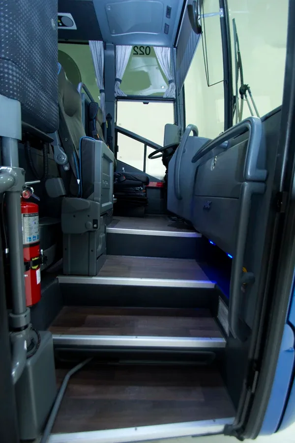 Charter motorcoach interior entry stairwell with steps, grab rails and mounted fire extinguisher