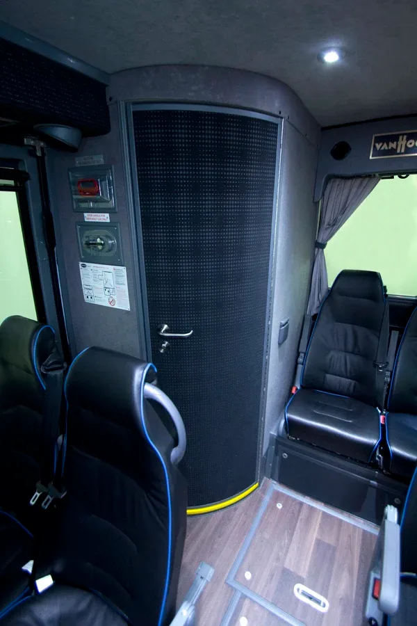 Charter motorcoach interior showing onboard restroom door beside rear passenger seating
