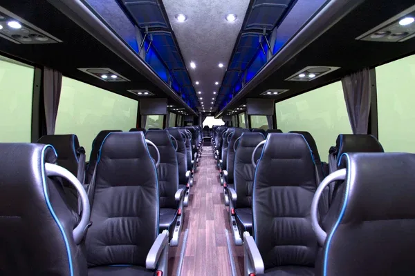 Charter motorcoach interior, rows of reclining seats with blue accent lighting along center aisle