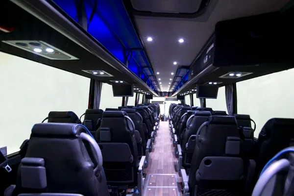 Charter motorcoach interior facing rear, leather seats with overhead lighting and center aisle