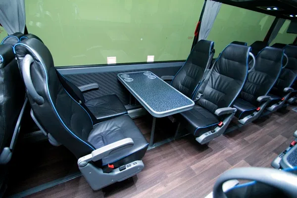 Charter motorcoach interior seats with deployed fold-out tray tables and wood-look flooring
