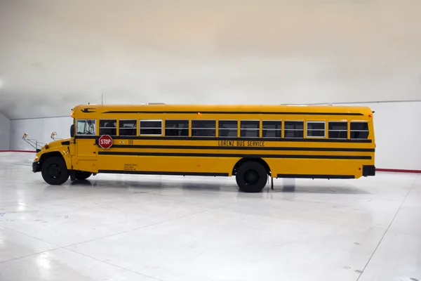Lorenz Bus Service yellow school bus parked indoors, side profile view