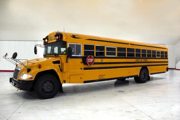 Lorenz Bus Service yellow school bus parked indoors, showing full side profile with stop sign and fleet number 111