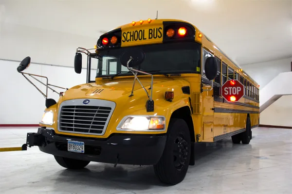 Yellow school bus with lights and stop sign deployed, parked inside a facility