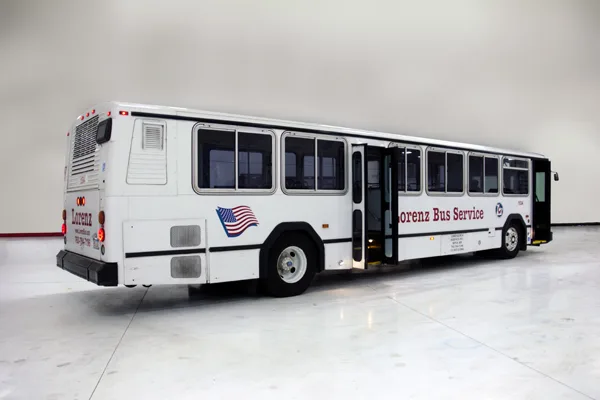 Lorenz Bus Service full-size white transit bus with American flag logo, shown from the rear three-quarter angle