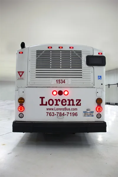 Rear view of a Lorenz Bus Service coach displaying the company name, website, and phone number 763-784-7196