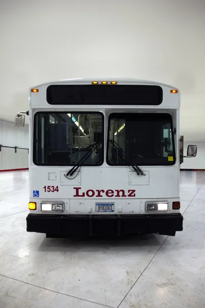 Front view of a white Lorenz bus, number 1534, with ADA accessibility symbol, parked inside a maintenance facility