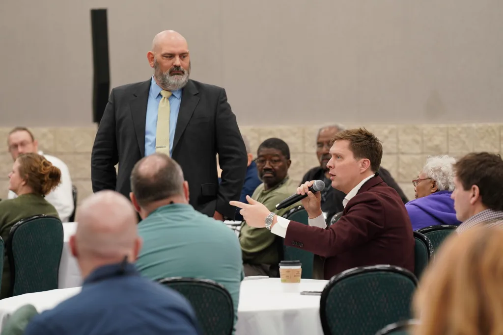 Attendee speaking into a microphone while another listens during a Lorenz Bus Service industry meeting discussion