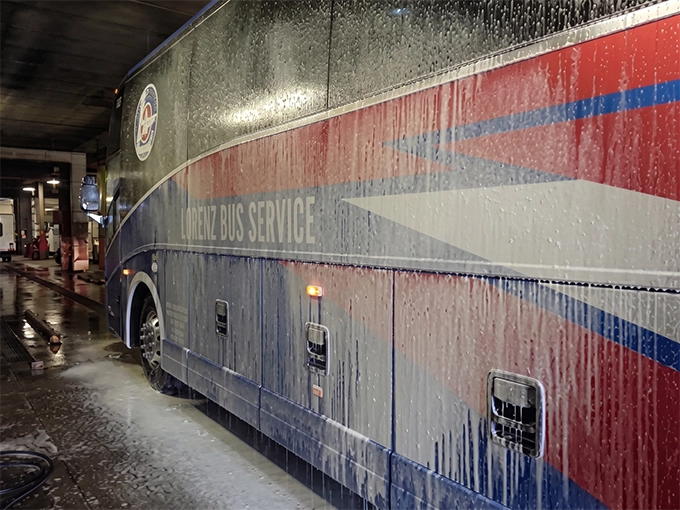 Lorenz Bus Service motorcoach covered in soap suds during wash and detailing inside the cleaning bay