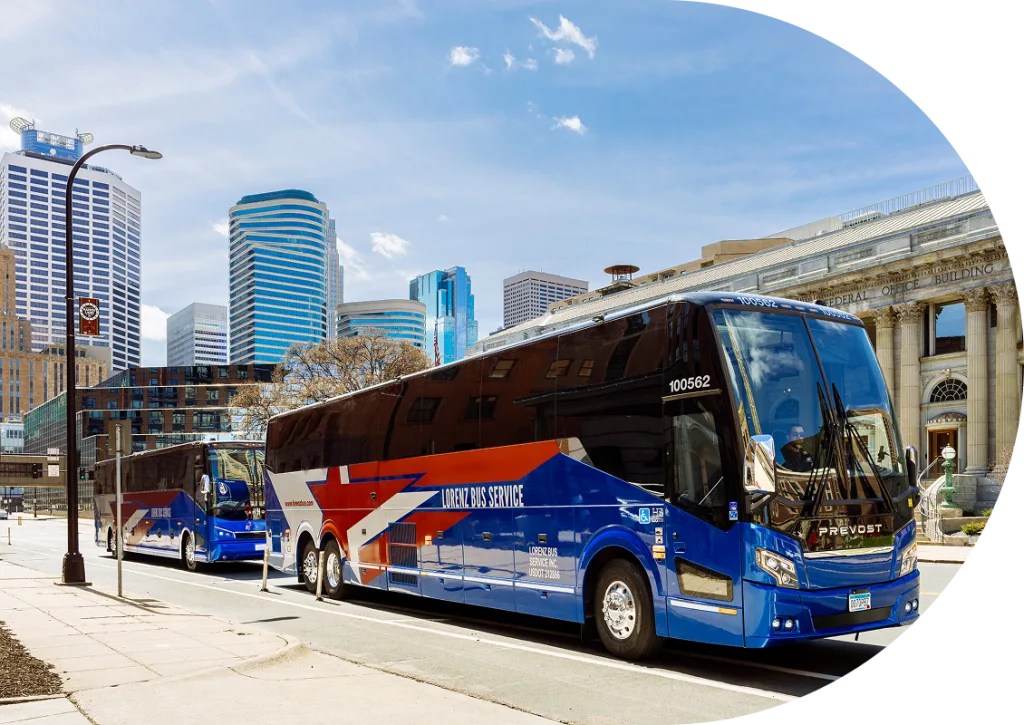 Two Lorenz Bus Service Prevost motorcoaches parked on a downtown Minneapolis street with skyline and Federal Office Building