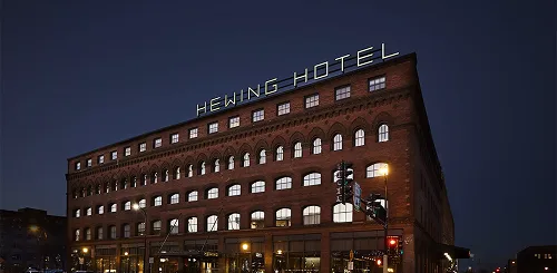 Hewing Hotel exterior at night, a historic red brick building with illuminated rooftop signage in Minneapolis