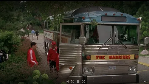 Vintage Lorenz charter bus with The Warriors banner at a wooded drop-off in a screenshot from D3 The Mighty Ducks