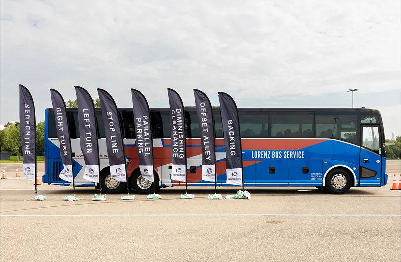 Lorenz Bus Service motorcoach parked beside a row of driver training course flags including backing, offset alley, and serpentine