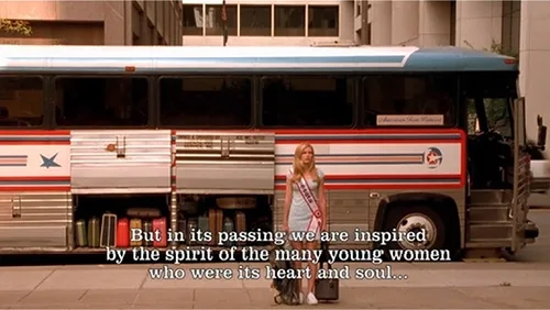 Woman in pageant sash standing beside a Lorenz charter bus on a city street in a screenshot from Drop Dead Gorgeous