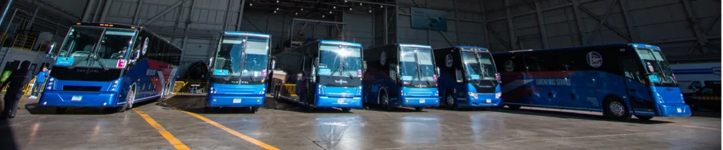 Six blue Lorenz Bus Service Van Hool motorcoaches lined up inside a large depot garage