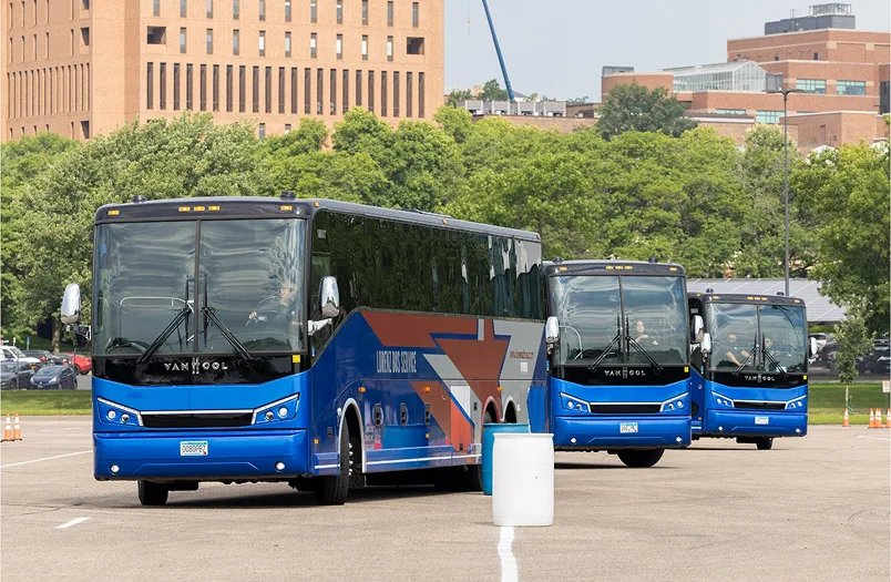 Three blue Lorenz Bus Service Van Hool motorcoaches navigating a driver training course in an open parking lot