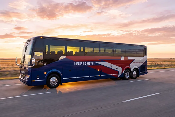 Lorenz Bus Service motorcoach traveling on an open highway at sunset