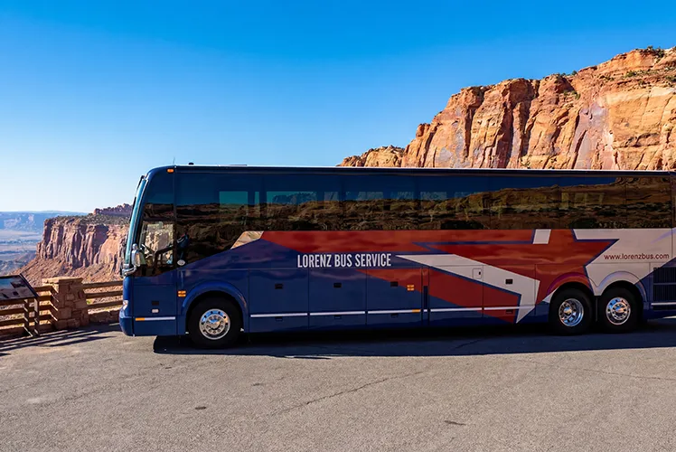 Lorenz Bus Service motorcoach parked at a red rock canyon overlook under a clear blue sky