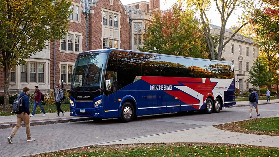 Lorenz Bus Service Prevost charter coach parked on a college campus in autumn, with students walking nearby