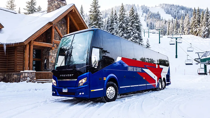 Lorenz Bus Service motorcoach parked at a snowy ski resort, with a ski lift and snow-covered slopes in the background