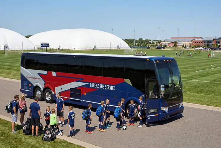 Youth soccer players boarding a Lorenz Bus Service Prevost coach at a sports complex