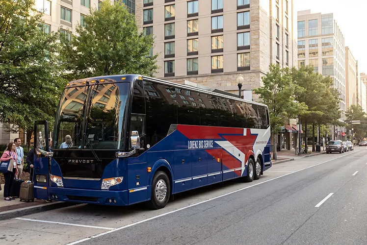 Lorenz Bus Service Prevost motorcoach parked on a city street as passengers with luggage board