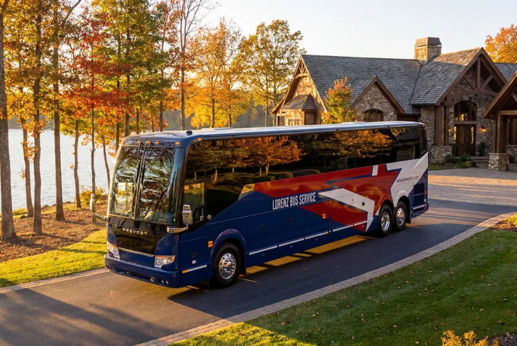 Lorenz Bus Service Prevost motorcoach parked at a lakeside estate surrounded by autumn foliage