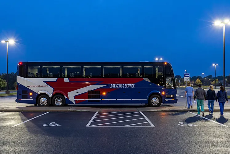 Lorenz Bus Service motorcoach parked at night as passengers walk toward the boarding door