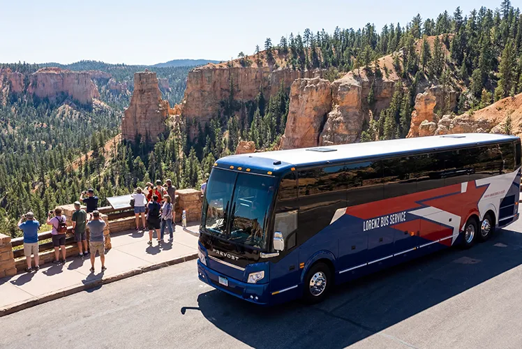 Lorenz Bus Service Prevost motorcoach parked at a scenic canyon overlook while passengers explore the viewpoint