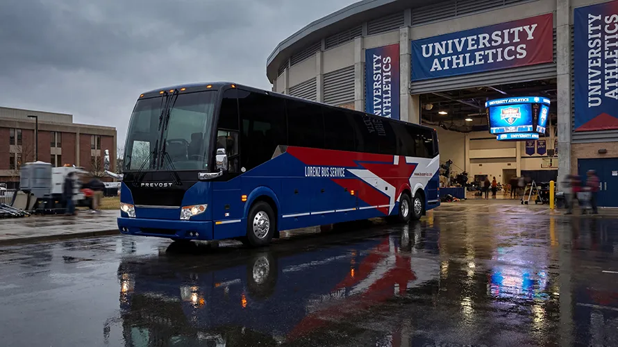 Lorenz Bus Service Prevost coach parked outside a university athletics arena, ready for team transport