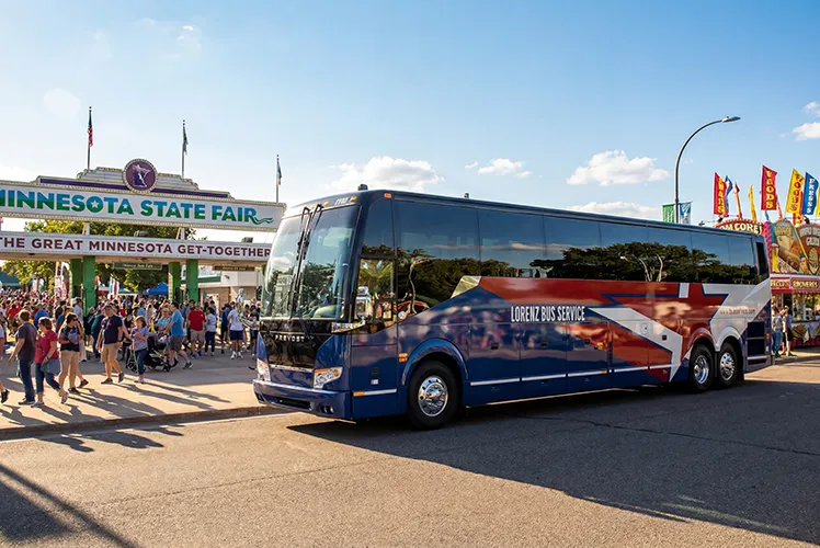 Lorenz Bus Service coach parked outside the Minnesota State Fair entrance with crowds of fairgoers nearby