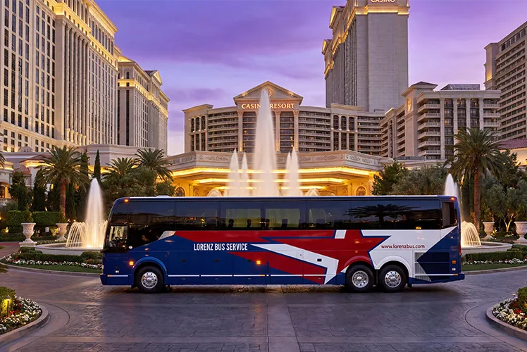 Lorenz Bus Service motorcoach parked in front of a Las Vegas casino resort with fountains at dusk