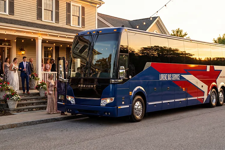 Lorenz Bus Service Prevost charter coach parked outside a wedding venue at sunset as guests in formal attire board