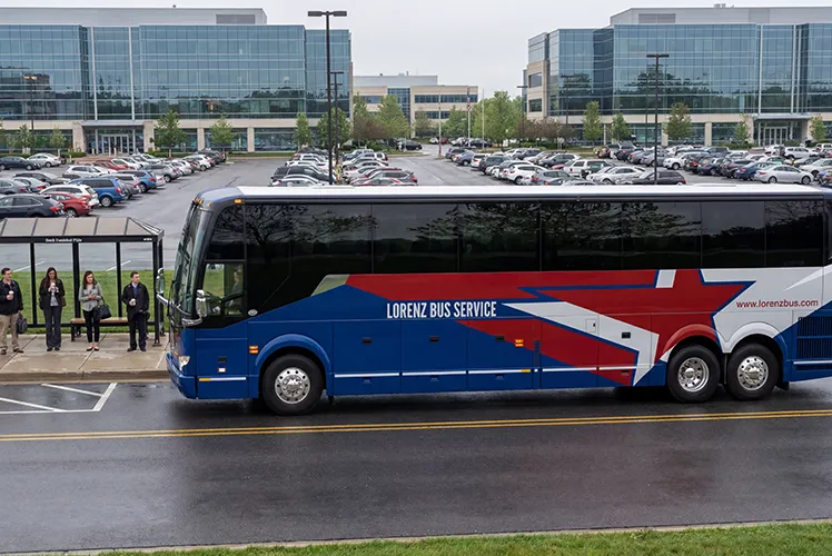 Lorenz Bus Service motorcoach picking up passengers outside a corporate office complex