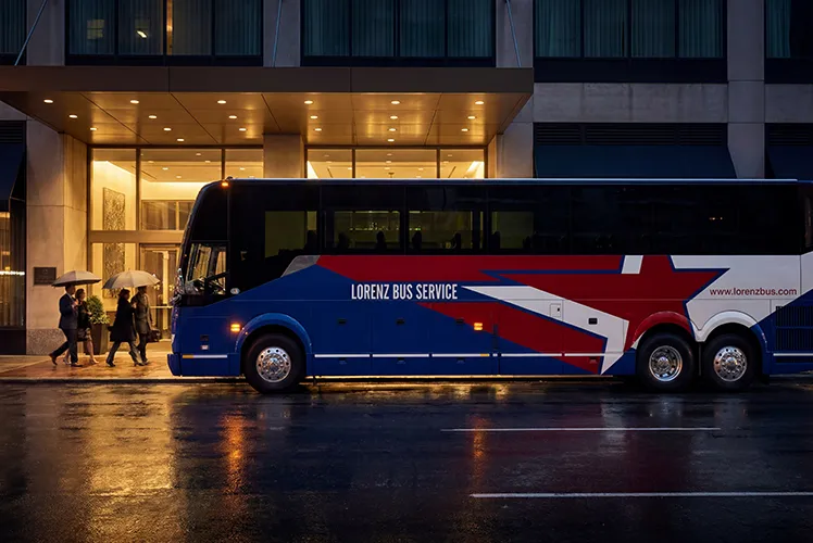 Lorenz Bus Service motorcoach parked outside a hotel entrance at night as passengers board in the rain