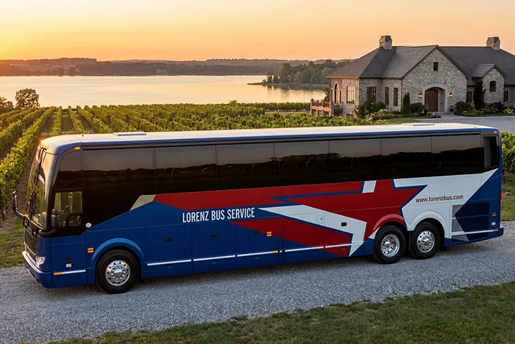 Lorenz Bus Service motorcoach parked at a lakeside vineyard venue at sunset