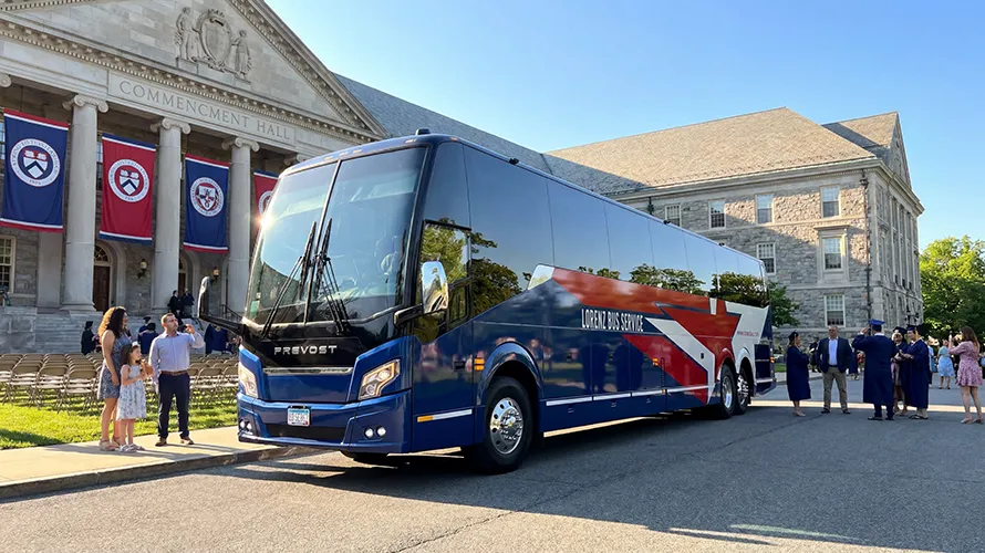 Lorenz Bus Service Prevost charter coach parked outside a university Commencement Hall during a graduation ceremony