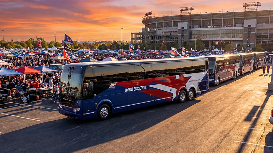 Lorenz Bus Service motorcoaches staged in a stadium parking lot surrounded by tailgating fans at sunset