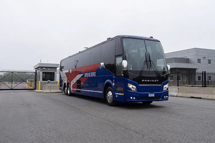 Lorenz Bus Service Prevost motorcoach parked outside a secured facility entrance