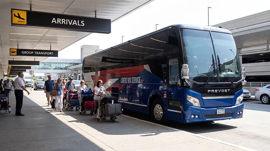 Lorenz Bus Service Prevost coach at an airport arrivals curb as a group of travelers with luggage prepares to board